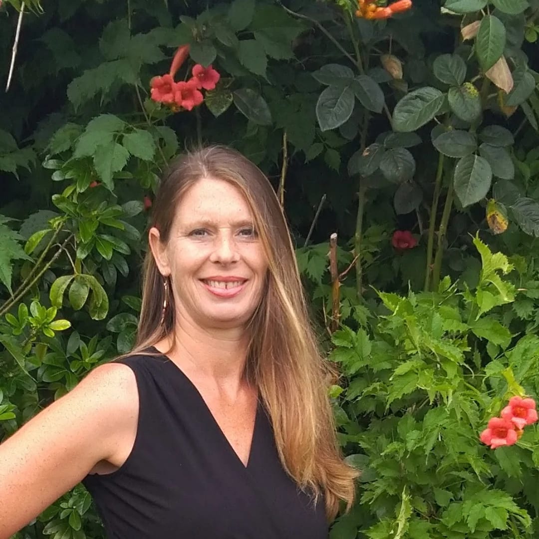 Séverine, thérapeute en Ayurvéda, devant des plantes en fleurs